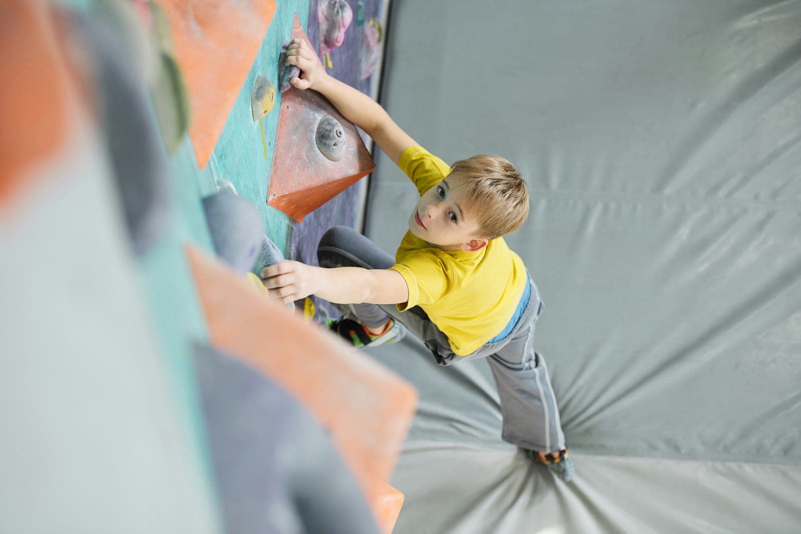 Enfant en t-shirt jaune grimpant sur un mur de bloc