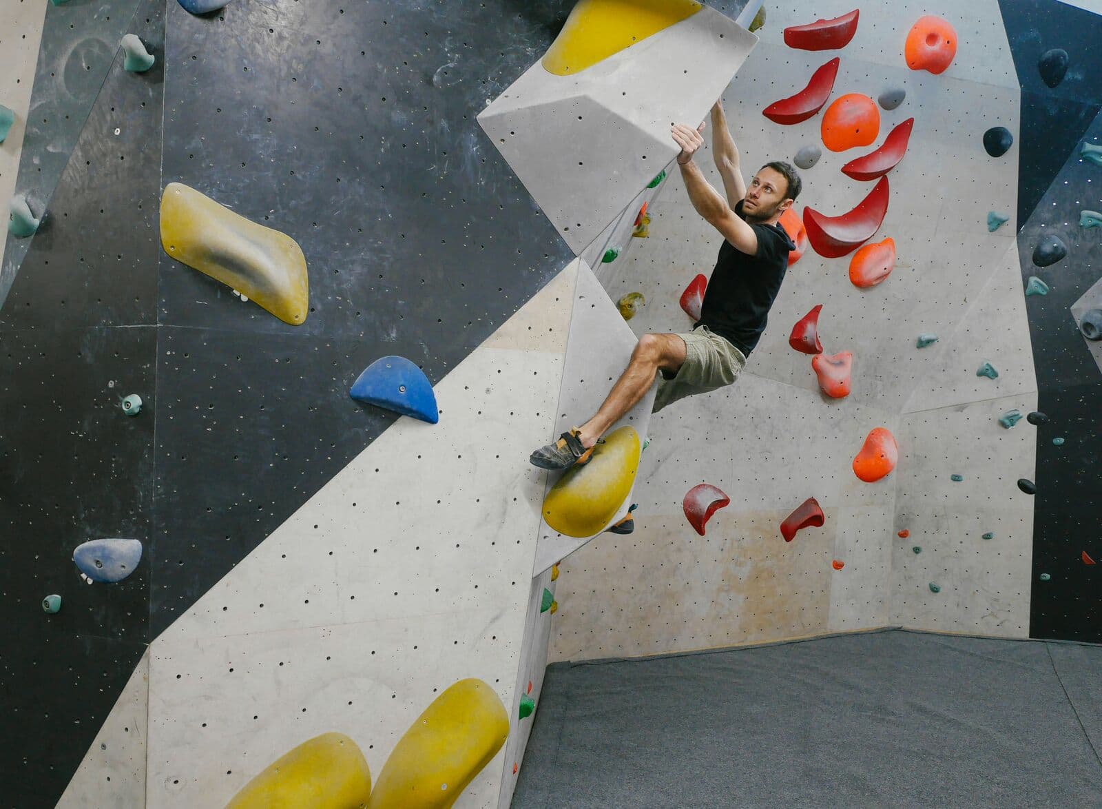 Grimpeur en appui sur un volume jaune au sommet d’une arête de bloc