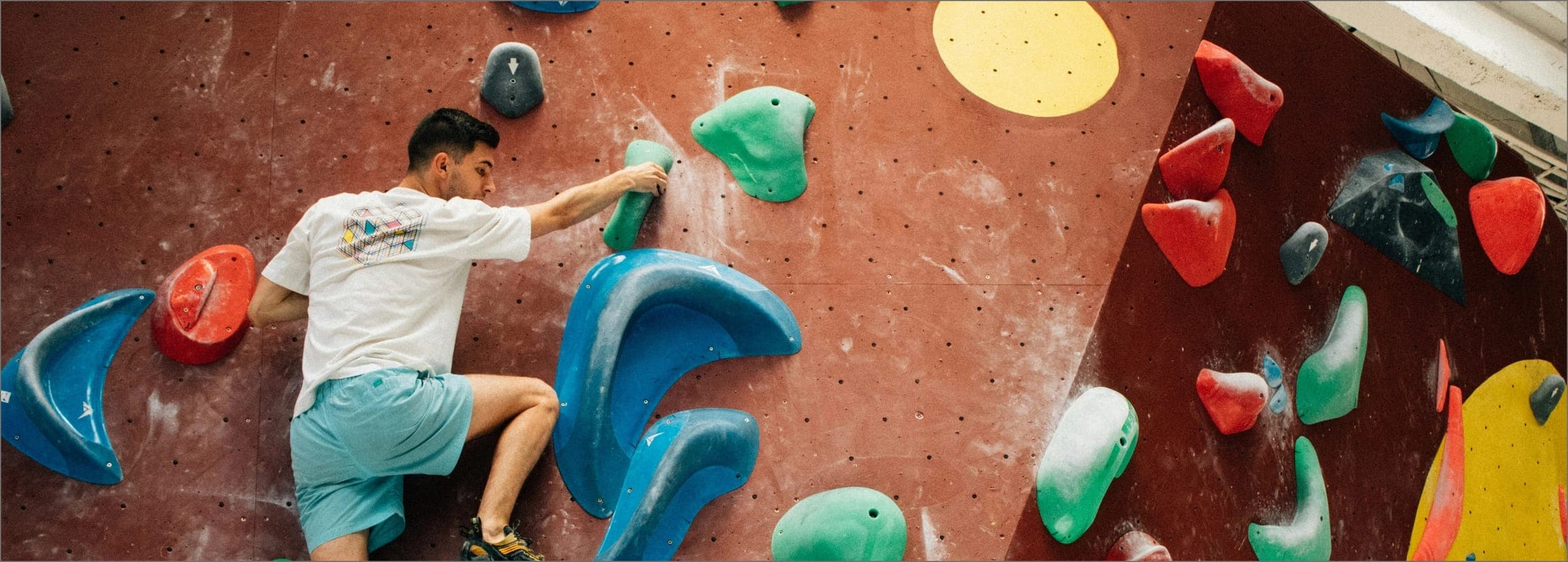Grimpeur débutant sur un mur de bloc en salle
