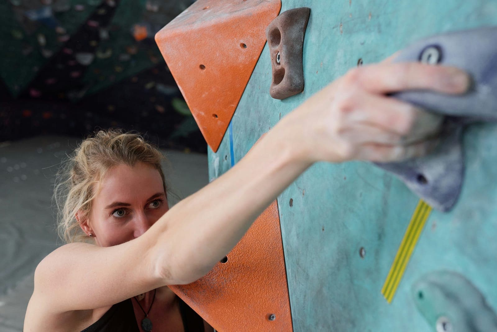 Grimpeuse tendant le bras vers une prise sur un mur de bloc
