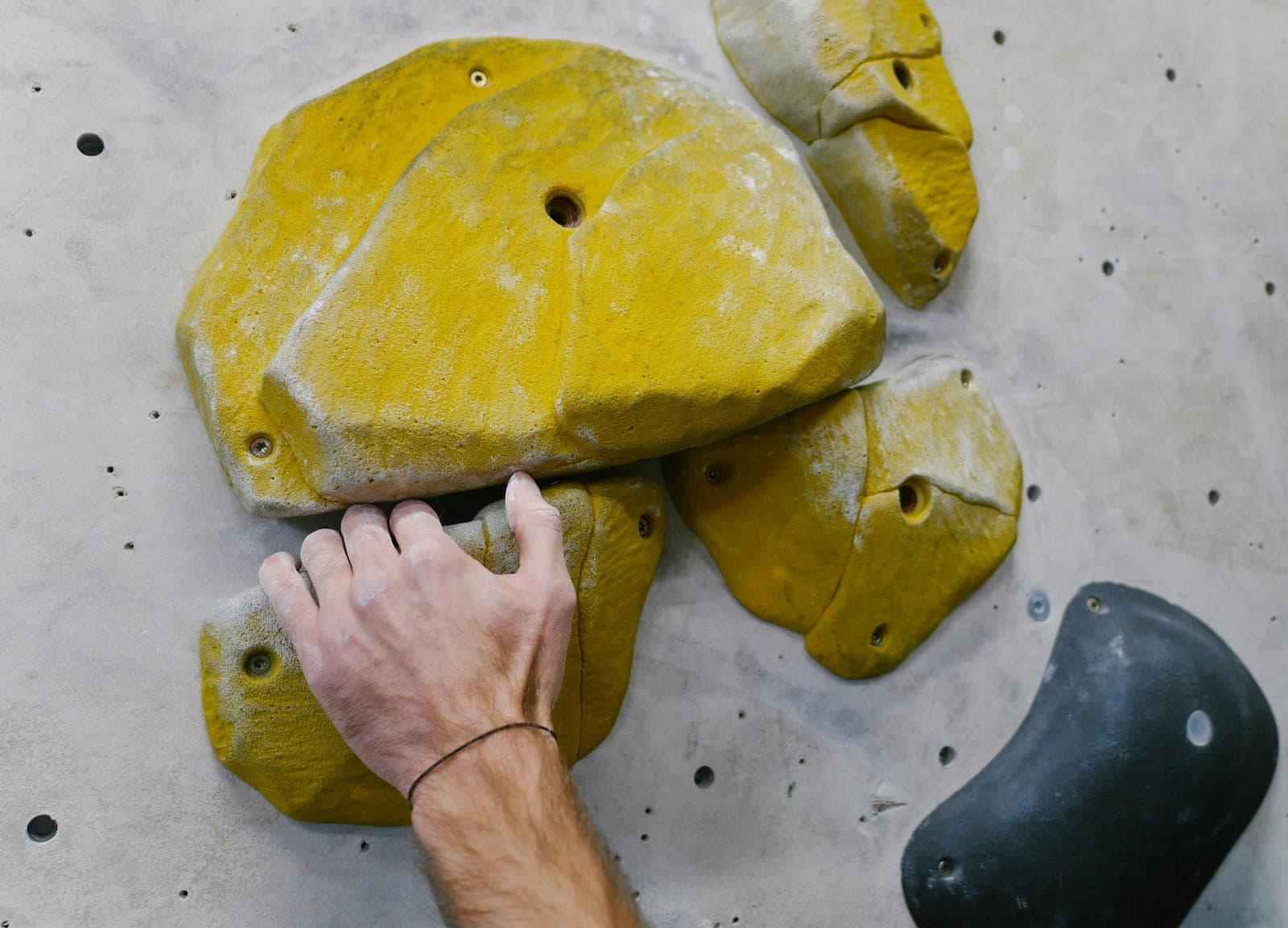 Main agrippant un volume jaune sur un mur de bloc gris